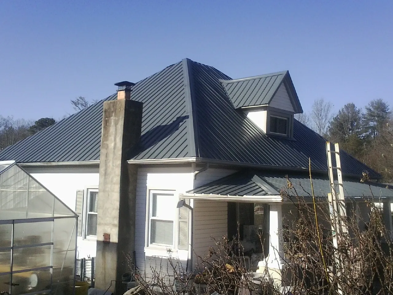 Dark blue standing seam metal roof on a white farmhouse with dormer — Slate & Tile Roof Repair by Roofing Brothers in Philippi