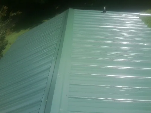 New green metal panels meeting at the ridge of a roof — Flat Roof Repair work by our crew in Philippi