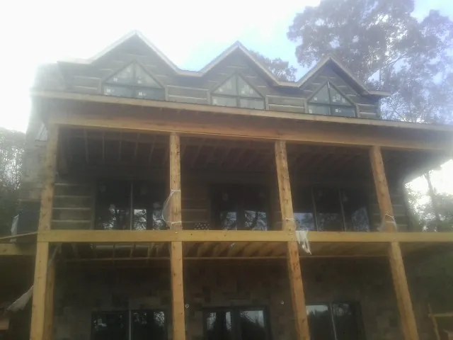 Dormers and porch framing on a large log home under construction — Roof Coating work by our crew in Philippi