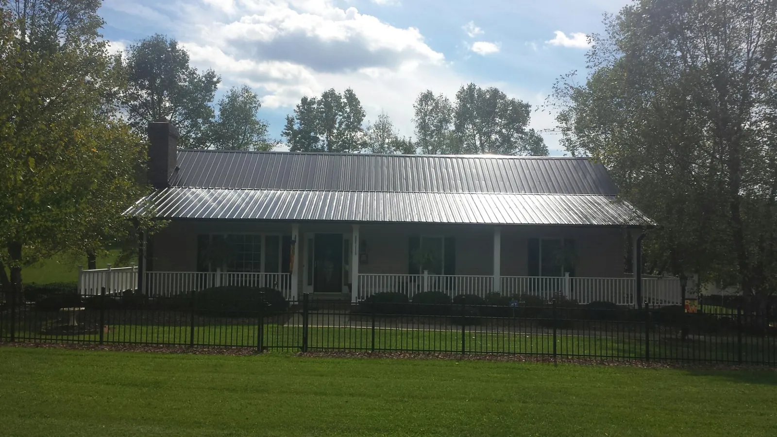 Gray metal roof on a brick ranch with a full width front porch — Gutter Guard Installation work by our crew in Philippi