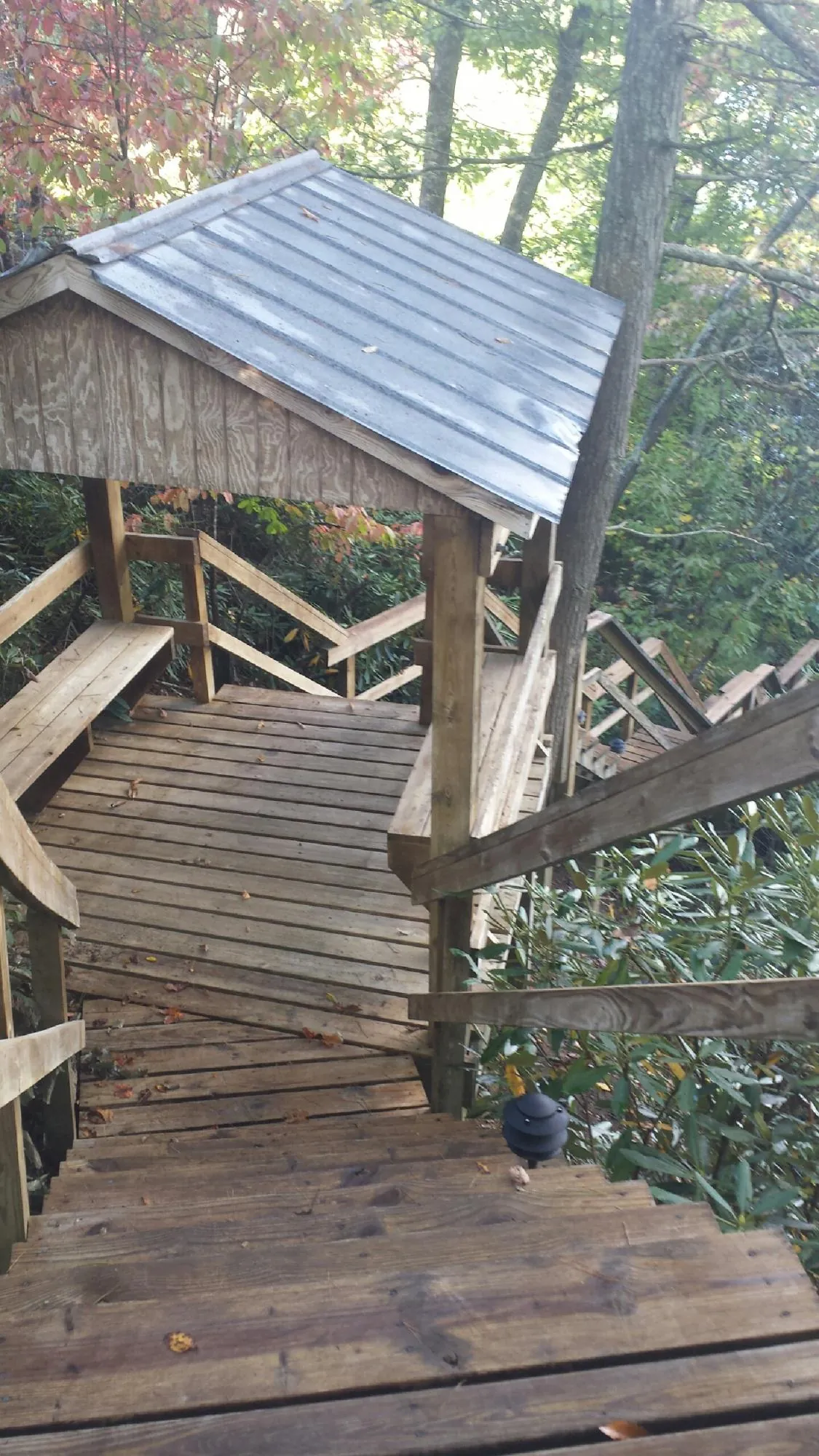 Metal roofed shelter over wooden steps on a wooded walkway — Skylight Repair & Installation work by our crew in Philippi