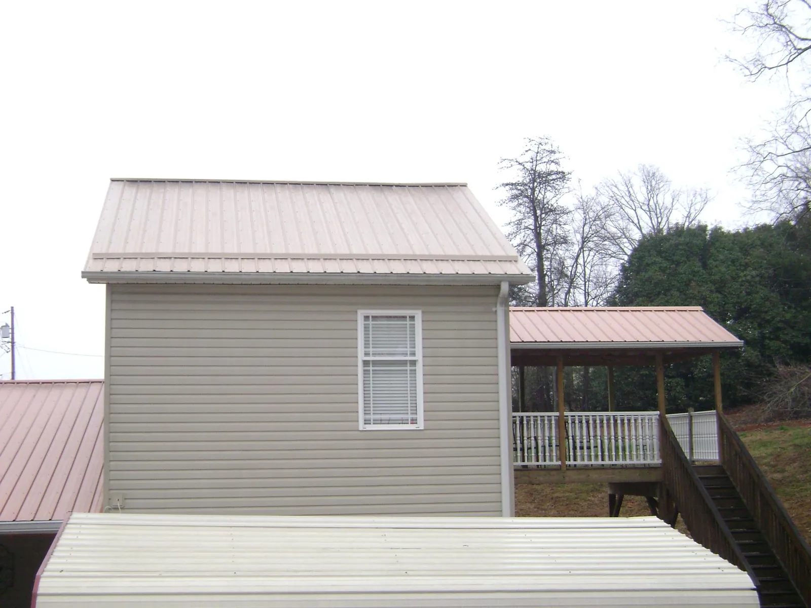 Tan metal roofs on a two story addition and attached porch, from a Roof Replacement job in Philippi
