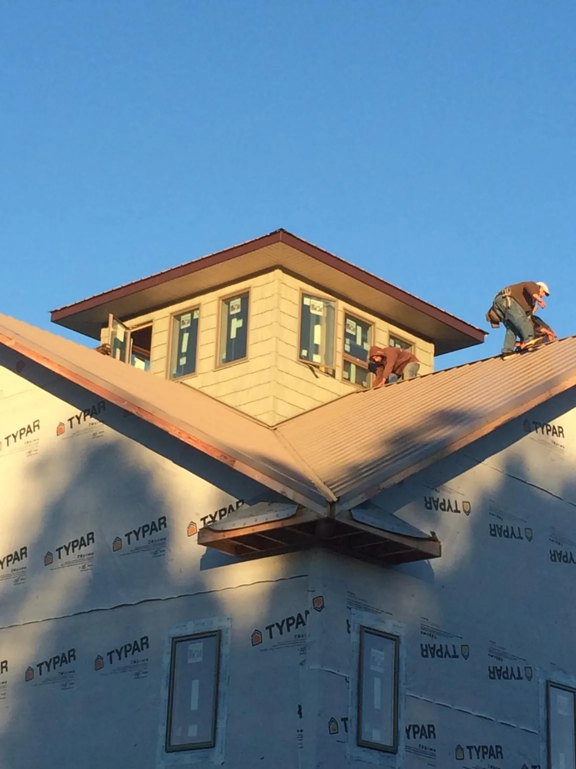 Roofers working around a rooftop cupola on a new metal roof at sunset — Roof Waterproofing in Philippi by Roofing Brothers